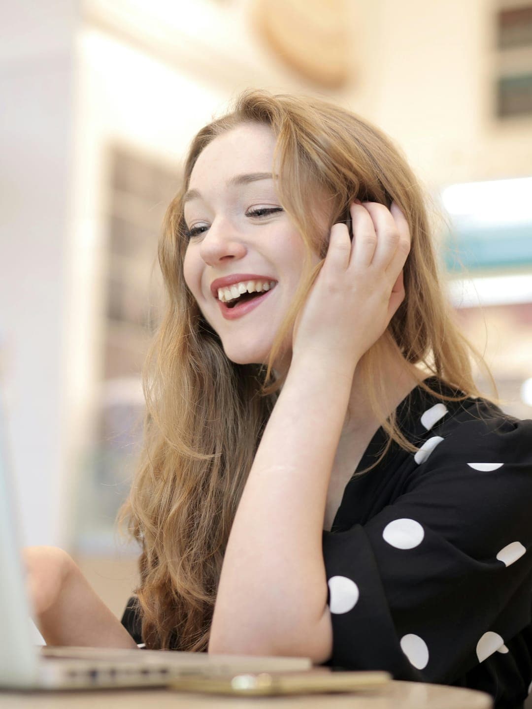 Happy ethnic woman sitting at table with laptop