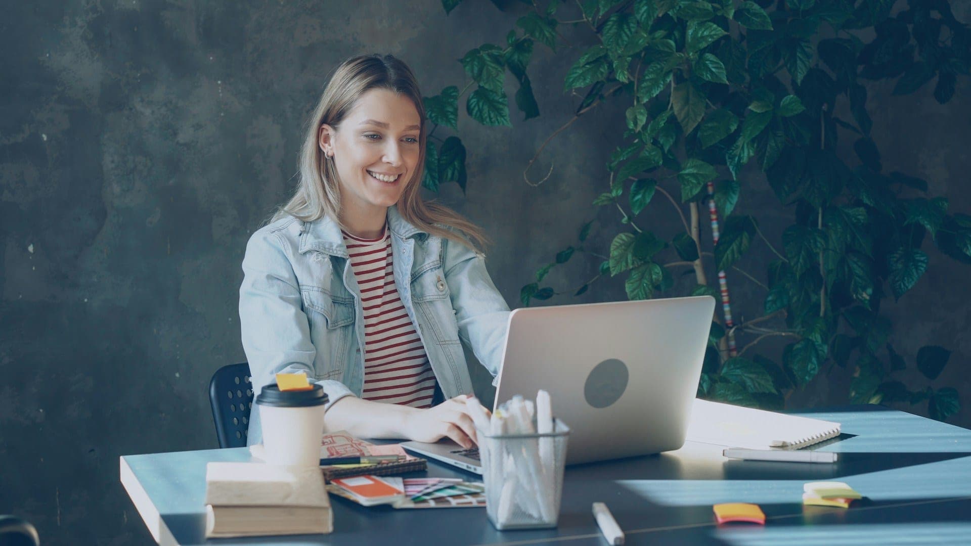 Happy ethnic woman sitting at table with laptop