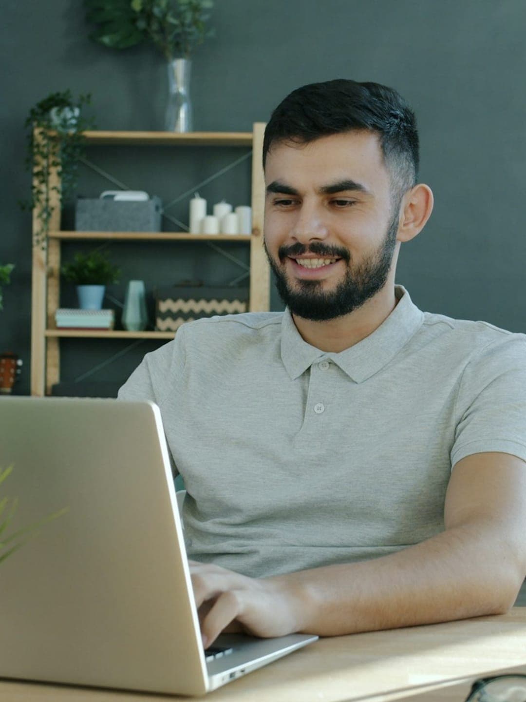 Happy ethnic woman sitting at table with laptop