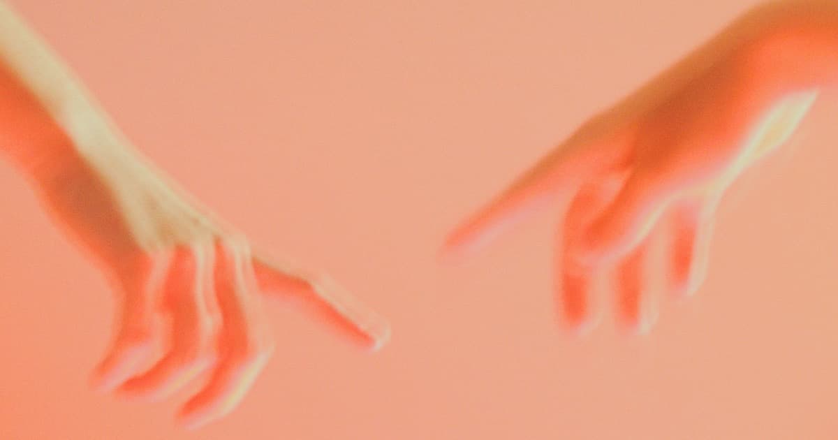 Two hands moving towards each other in front of a warm, bright background