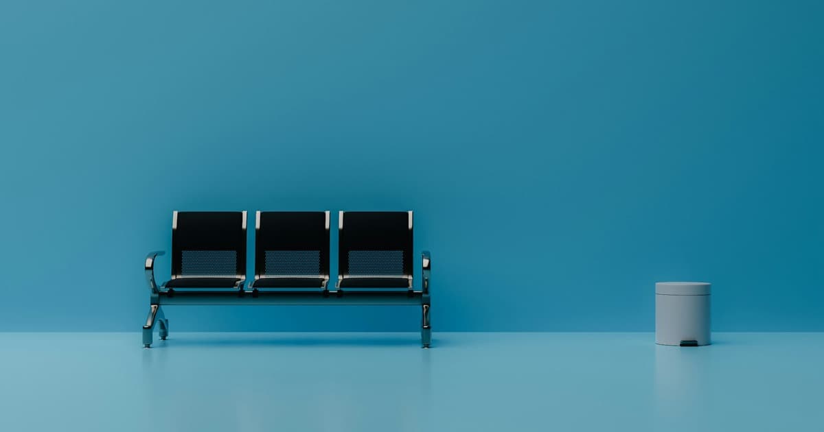 Leere Stühle vor einer blauen Wand als Symbol für lange Wartezeiten auf Psychotherapie